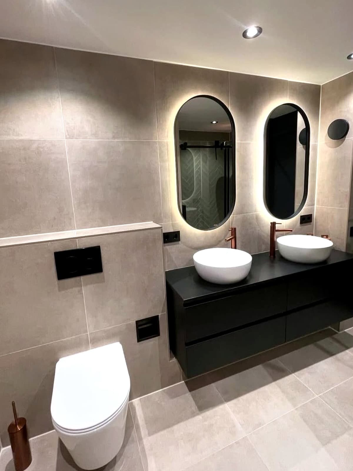 Badkamer met beige wandtegels, dubbele waskommen en een hangend toilet