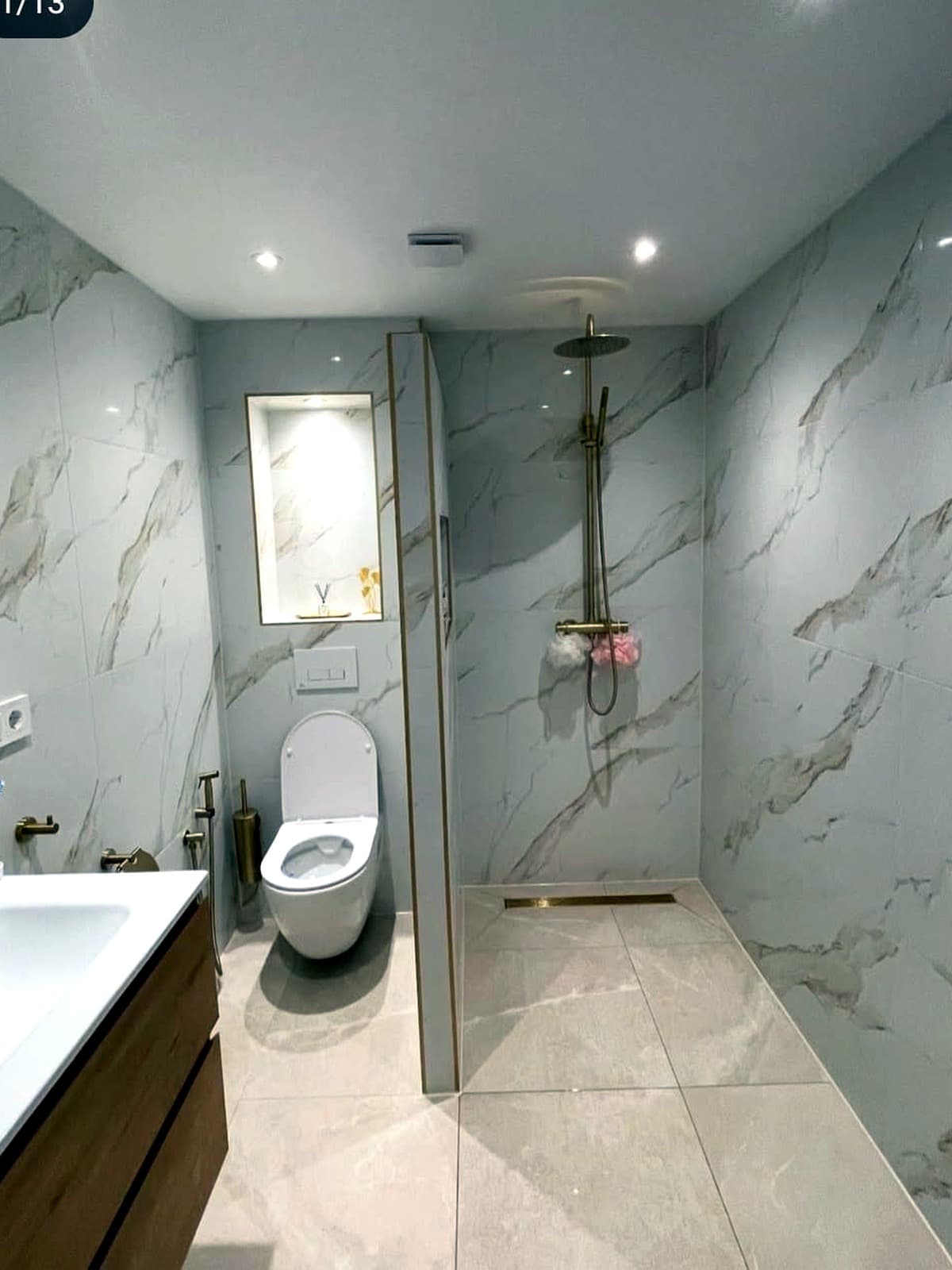 Badkamer met marmerlook tegels, inloopdouche en hangend toilet